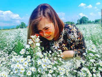 Woman wearing sunglasses looking at flowers growing on land