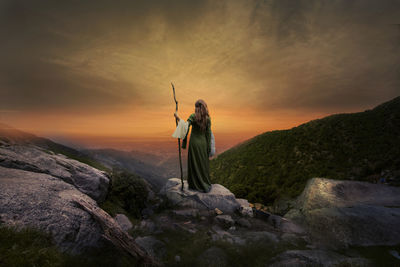 Man standing on mountain against sky during sunset