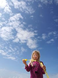Low angle view of girl holding bubble wand against sky