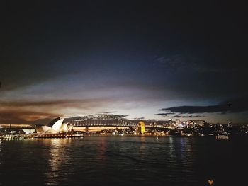 Illuminated bridge over river against sky in city at night