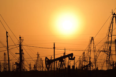 Silhouette electricity pylon against sky during sunset