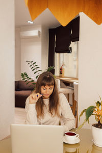 Woman home office and distance remote working. a young female businesswoman sitting at a desk 