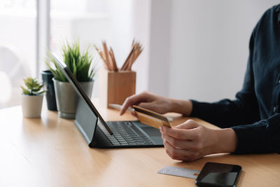 Midsection of woman using laptop on table