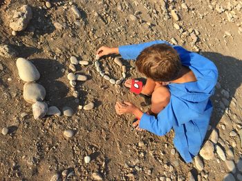 High angle view of child laying out words with stones on sand