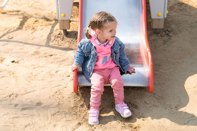 Full length of girl sitting on slide at playground