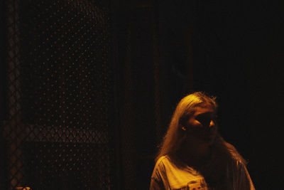 Portrait of woman standing against dark background