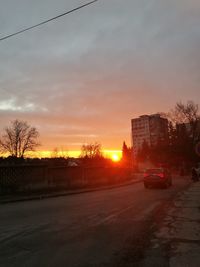 Cars on road against sky during sunset