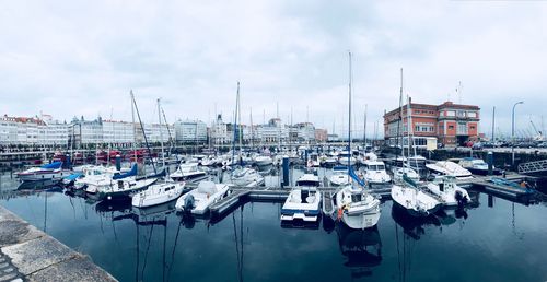 Boats moored at harbor against sky