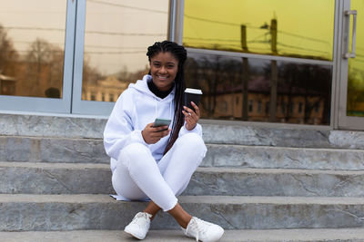 Young man using mobile phone while sitting on staircase