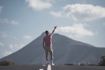 Woman with umbrella standing on mountain against sky