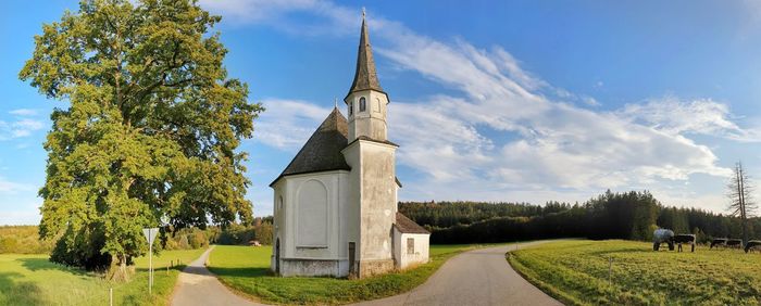 Panoramic shot of trees on field with church against sky