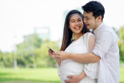 Young couple holding mobile phone outdoors