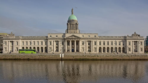 Building by river against sky in city