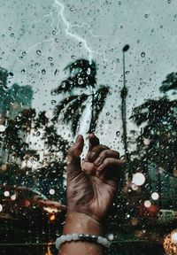 Close-up of hand by wet window in rainy season