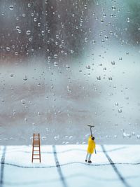 Tilt-shift image of man cleaning wet glass with wiper