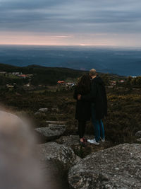 Rear view of man standing on mountain against sky during sunset