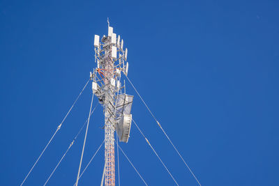 Low angle view of ferris wheel against clear blue sky