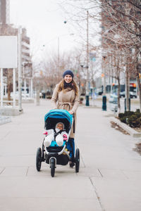 Portrait of smiling woman with baby walking on street
