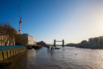 Bridge over river by buildings against sky