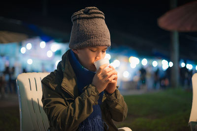 Full length of boy holding hat at night