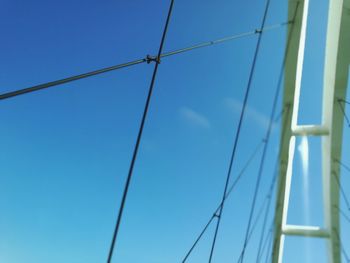 Low angle view of suspension bridge against clear blue sky