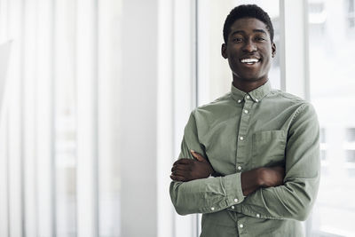 Portrait of young man standing against wall