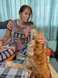 Woman playing with dog in bedroom at home