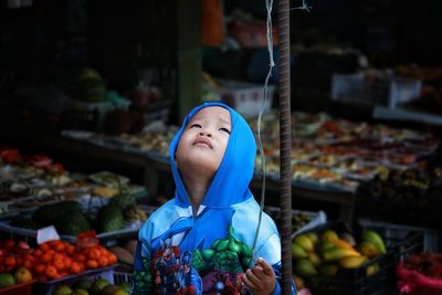 Boy standing amidst food at market stall