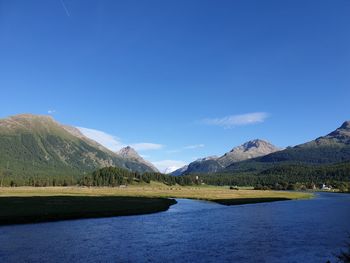 Scenic view of lake and mountains against blue sky