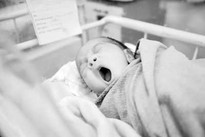 Close-up of baby yawing while lying in crib