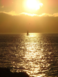 Silhouette of sailboat in sea during sunset