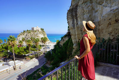 Girl enjoying view of the monastery of santa maria dell'isola of tropea. summer vacation in italy.
