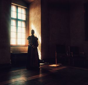 Rear view of man standing by window in temple