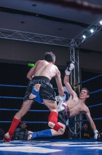 Full length of shirtless boxers fighting in ring