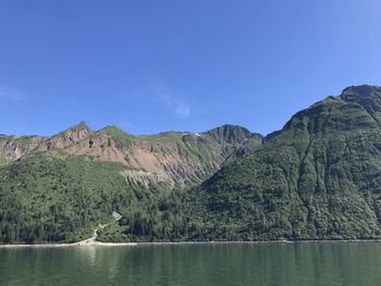 Scenic view of lake and mountains against blue sky