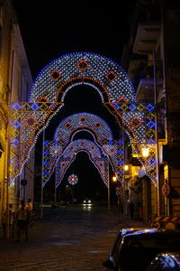 Illuminated city street against sky at night