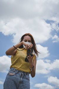 Low angle view of young woman standing against sky