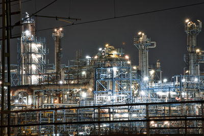 Illuminated factory against sky at night