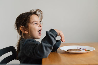 Cute girl eating food while sitting at home