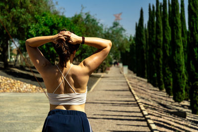 Rear view of woman standing on footpath amidst trees