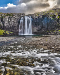 Scenic view of waterfall against sky