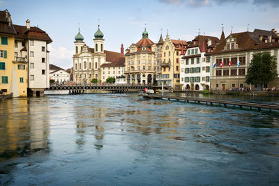 Buildings by river against sky in city