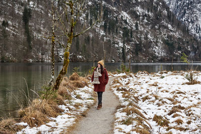 Young woman walking on a path by a lake. winter, snow, cold weather, outdoors.