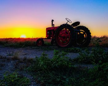Tractor on field against sky during sunset