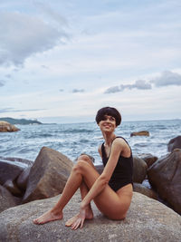 Young woman sitting on rock at beach