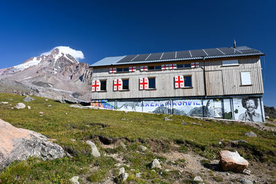 House on mountain against clear blue sky
