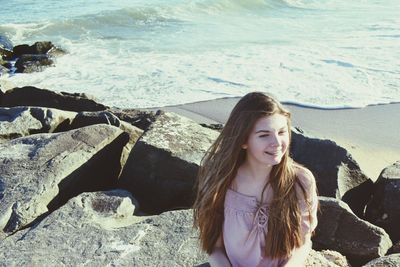 Young smiling woman on rocks at seashore