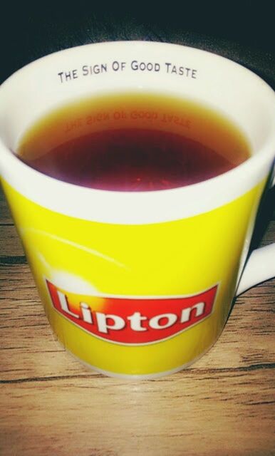 indoors, table, drink, still life, food and drink, yellow, refreshment, close-up, text, freshness, communication, western script, high angle view, wood - material, no people, coffee cup, focus on foreground, single object, cup, orange color