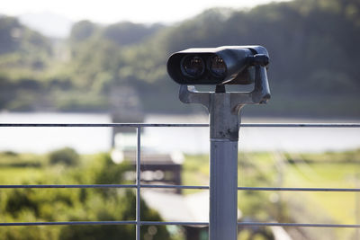 Coin-operated binoculars by railing against lake