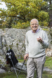Portrait of happy senior man holding golf ball and club in yard